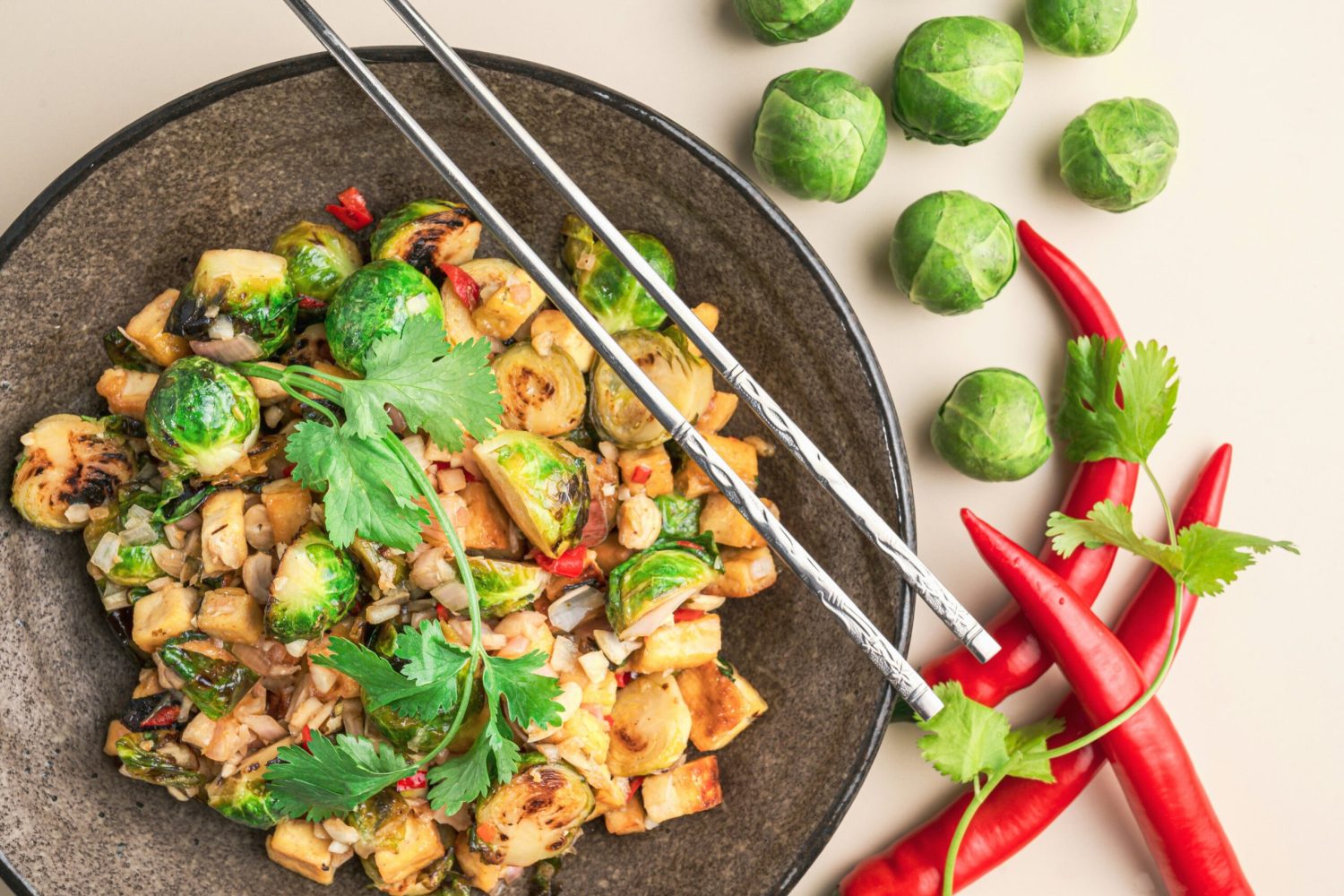A plate of tofu, Brussel sprouts, chilli with chopsticks