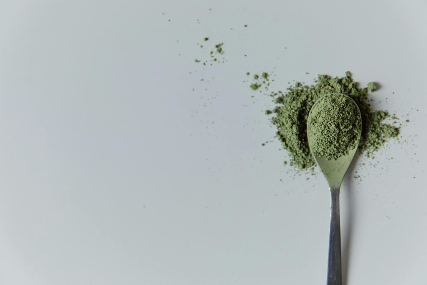Green powder on and spilling off a a spoon