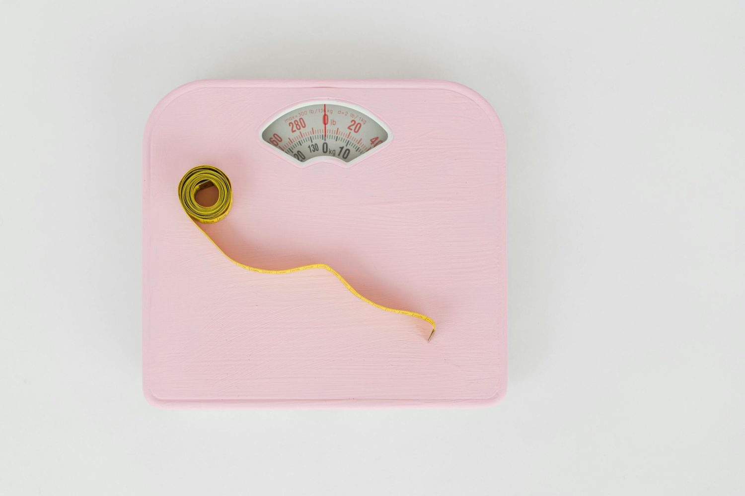 Pink bathroom scales with a measuring tape, symbolising weight management and healthy lifestyle change.